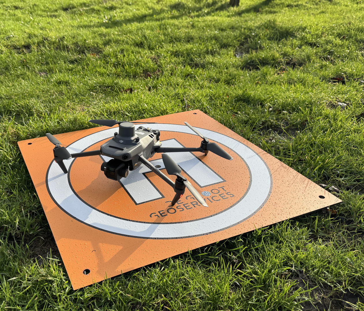 Drone op een landingsplaat met het logo van De Groot GeoServices, in het gras